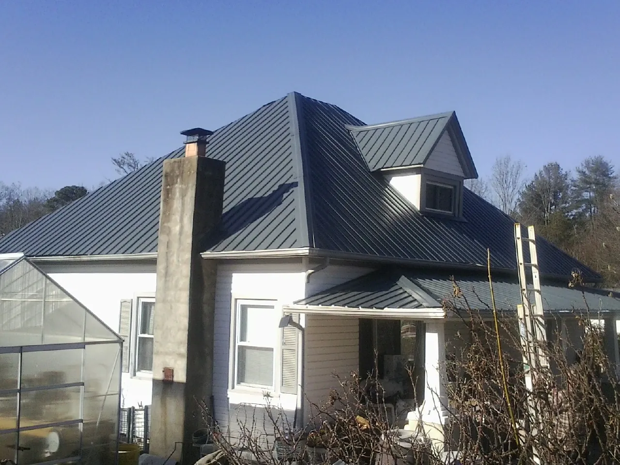 Dark blue standing seam metal roof on a white farmhouse with dormer — Slate & Tile Roof Repair by Roofing Brothers in Sandusky