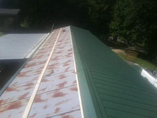 Old rusted panels beside newly installed green metal roofing — Wind Damage Roof Repair by Roofing Brothers in Sandusky