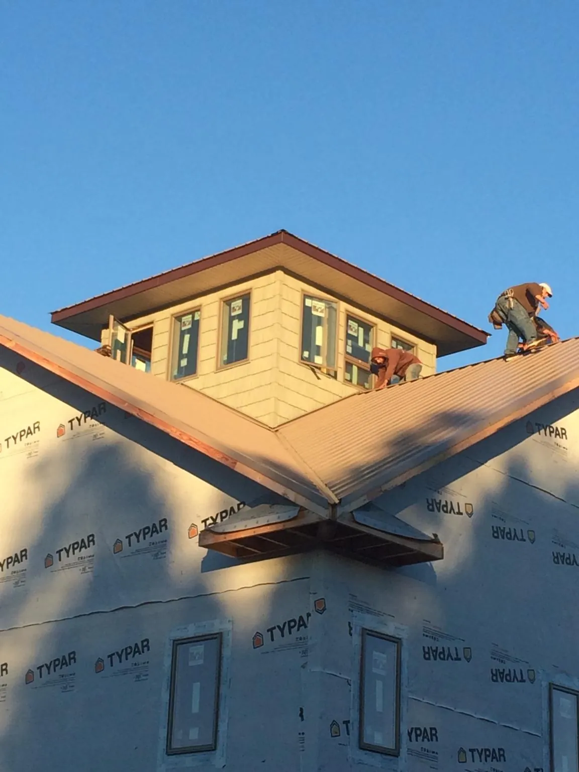 Roofers working around a rooftop cupola on a new metal roof at sunset — Roof Waterproofing in Sandusky by Roofing Brothers